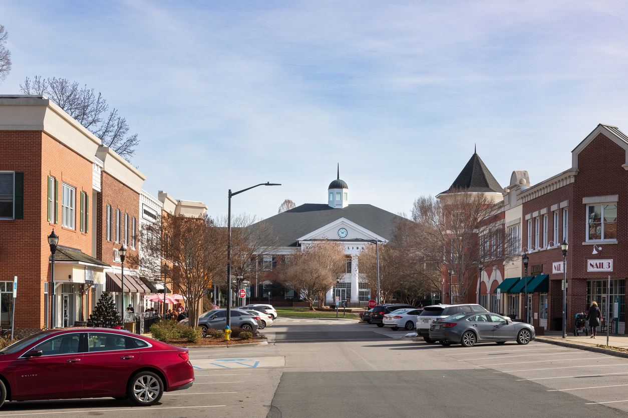 Tree-lined downtown streetscape with red-brick shops and parked cars in Matthews, NC