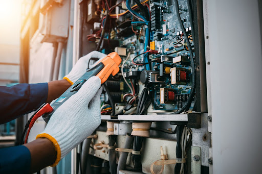 Technician is checking the air conditioner refrigerant system maintenance and checking the switchboard control.